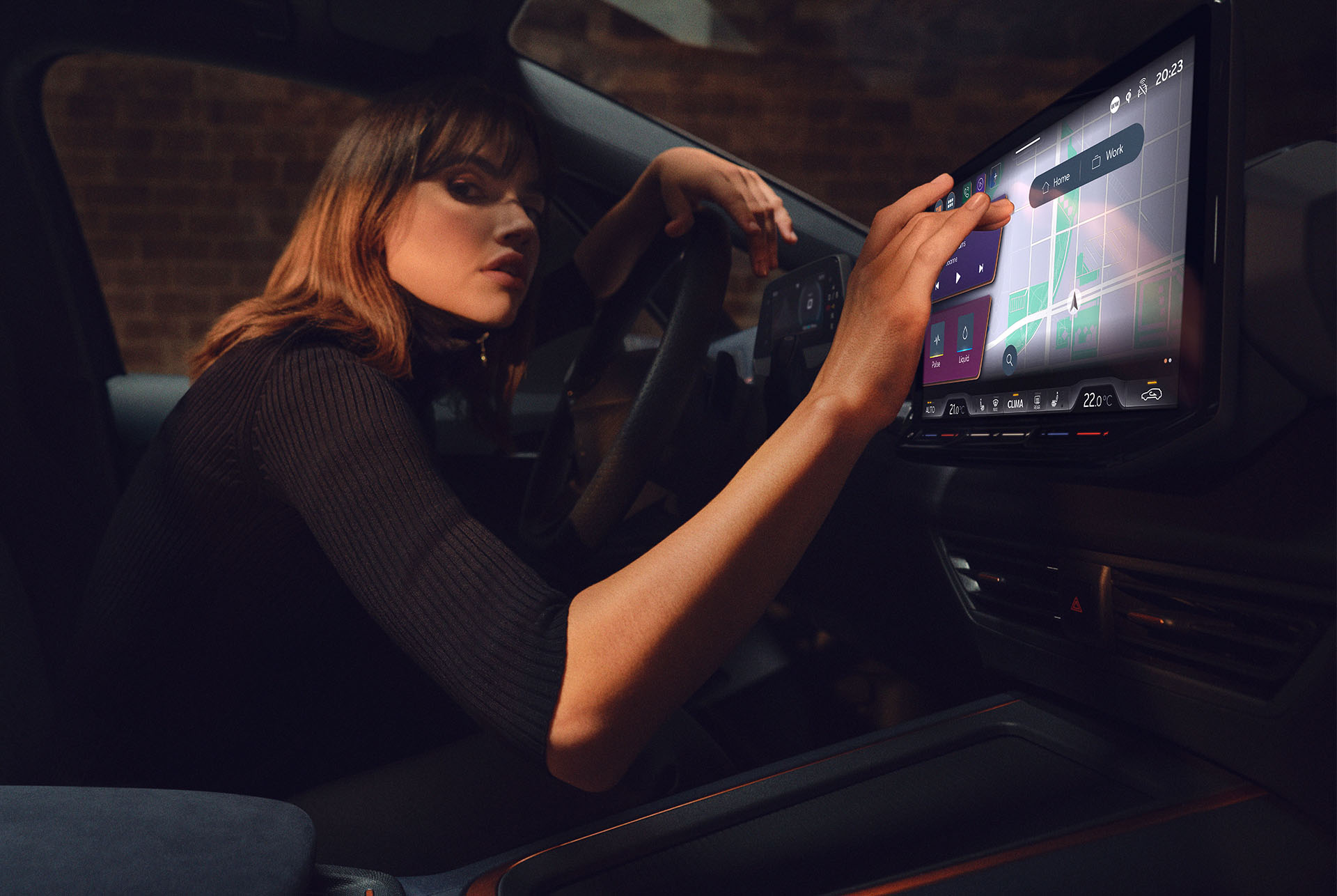 Woman inside a CUPRA Born using the dashboard and infotainment screen